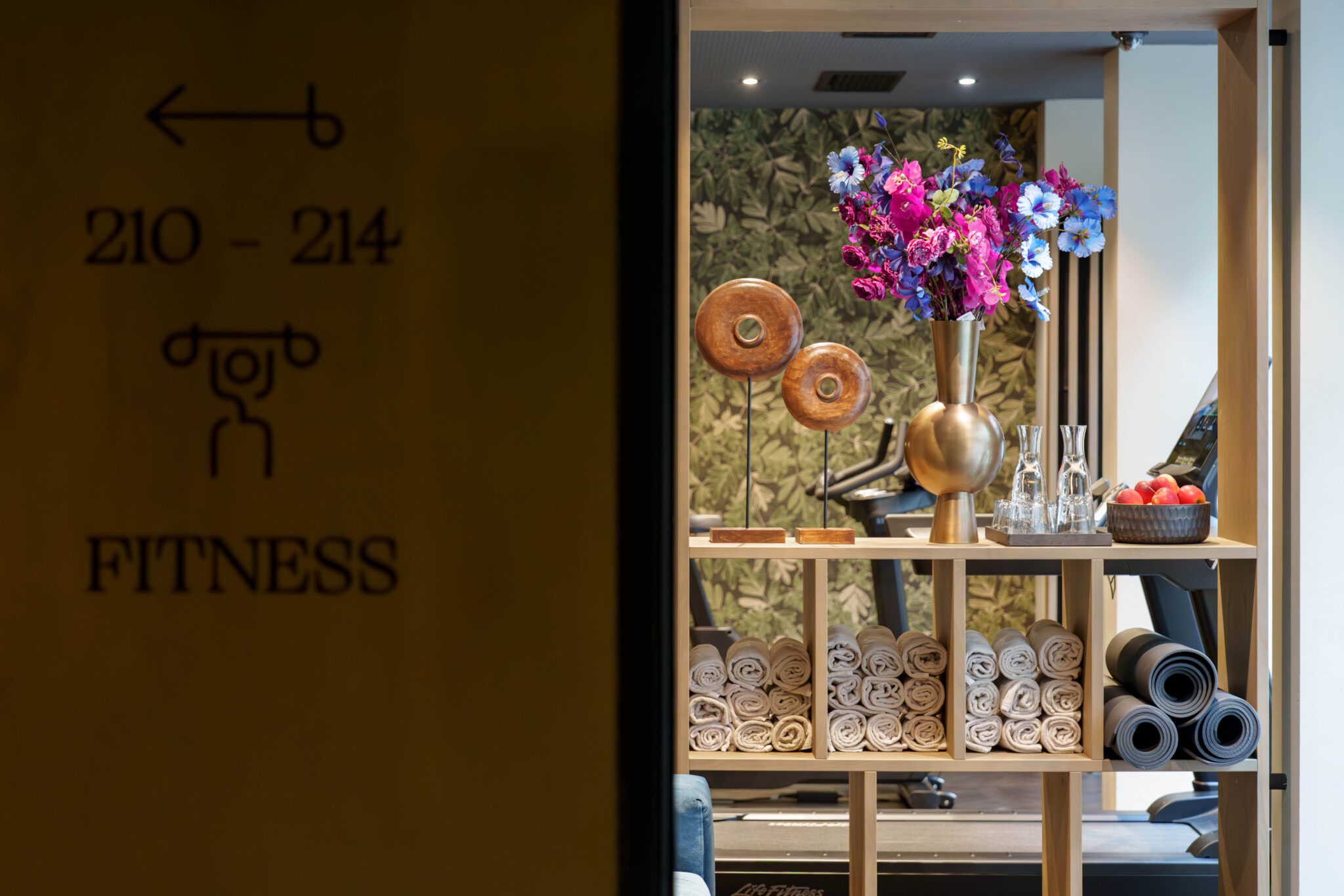 Blick in das Aiola Living Fitnessstudio mit Richtungsbeschreibungen an der Wand.